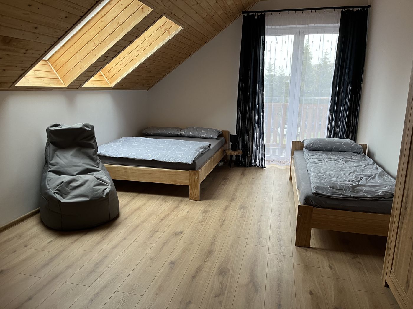 Podkrovná spálňa s manželskou posteľou, jednolôžkom a východom na balkón
